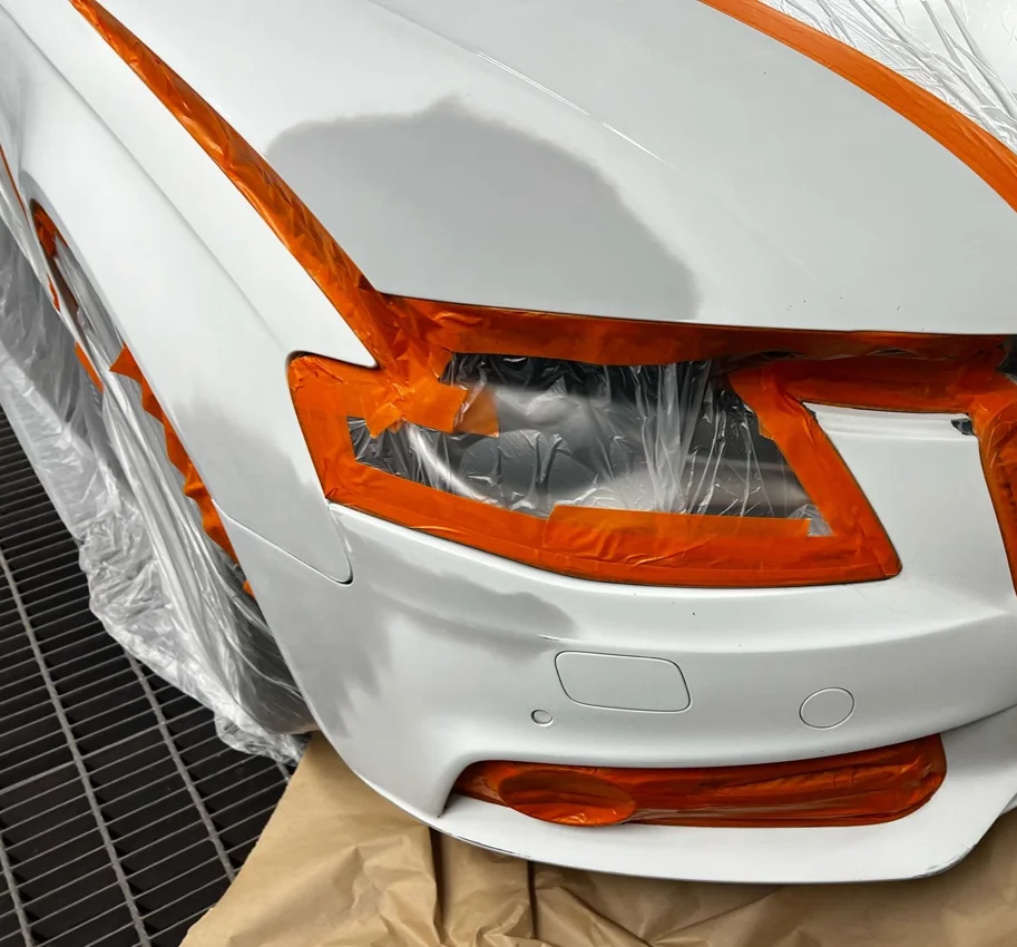 White vehicle bonnet and bumper masked for paint preparation