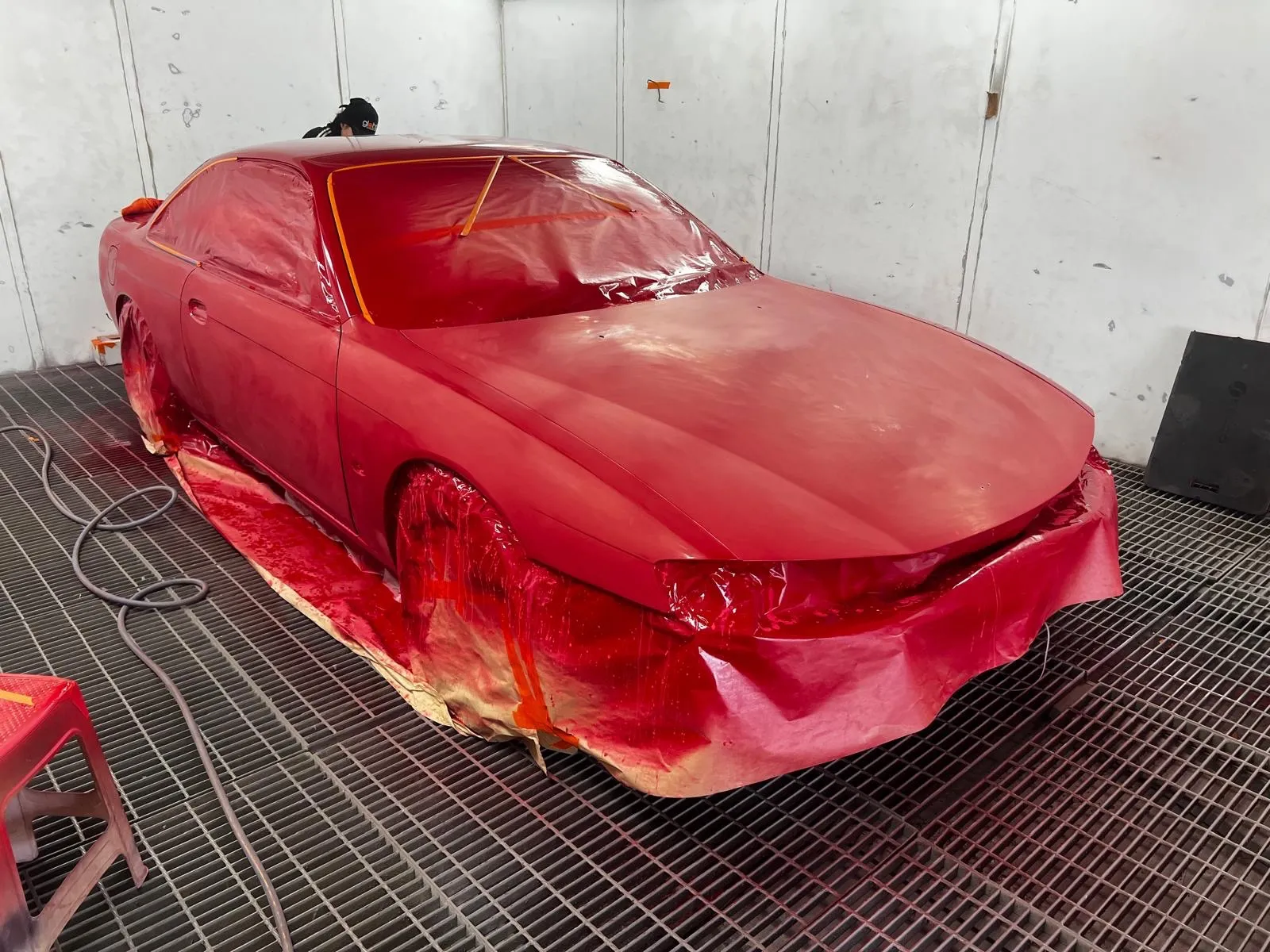 Red coupe sprayed in the booth with wheels and lower panels masked