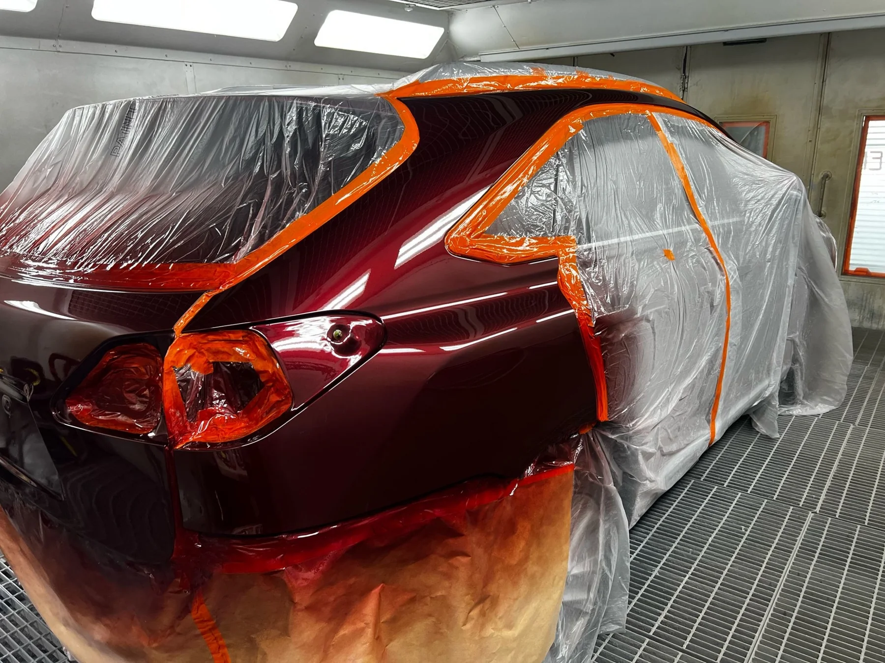 Freshly refinished burgundy vehicle panels with masking in the Lee Murdock Panels spray booth
